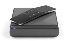 A small black media box with a remote on top. Android boxes used to power digital signage often look similar to this.